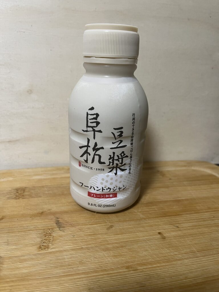 セブン-イレブンで買った阜杭豆漿(フーハンドウジャン)プレーン加糖290mLのボトル。木のまな板の上に立てて置いてある