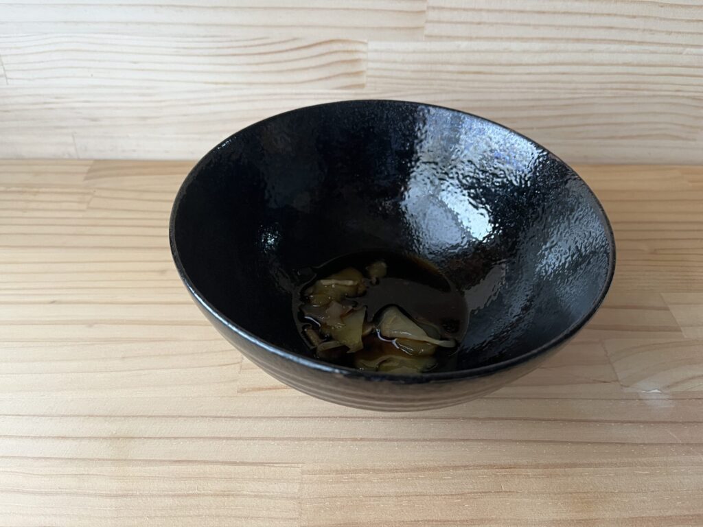 黒い器の底に、台湾しょうゆと工研烏醋、味付けザーサイだけを入れたところ。豆乳はまだ注いでいない