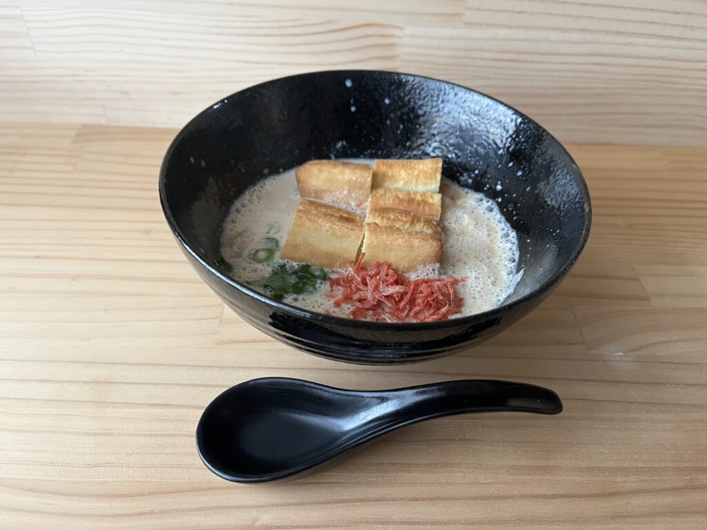 烏醋で作ったシェントウジャン。黒い器の豆乳スープに油條、刻みねぎ、干しえびがのり、れんげを添えている