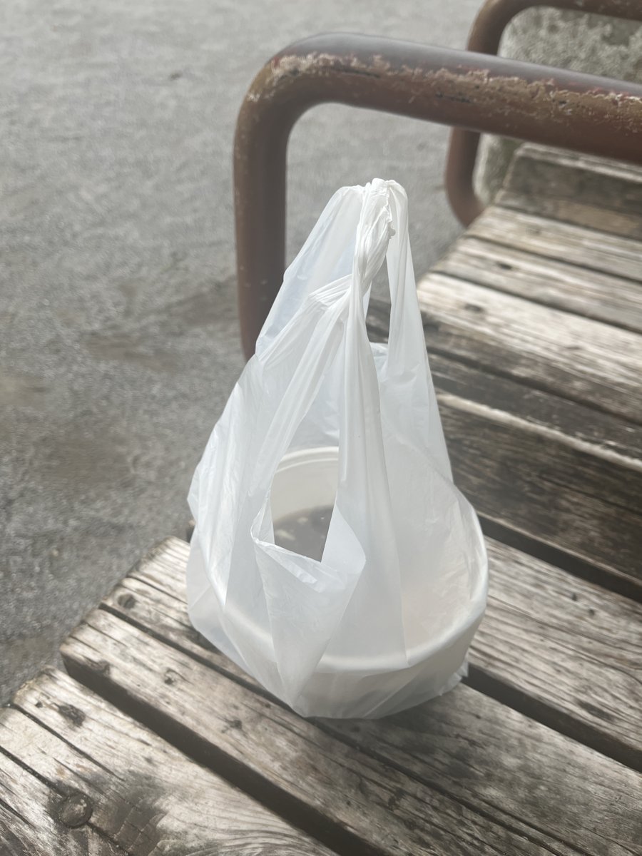 公園の木のベンチに置いた、持ち帰りの豆花が入った白いビニール袋