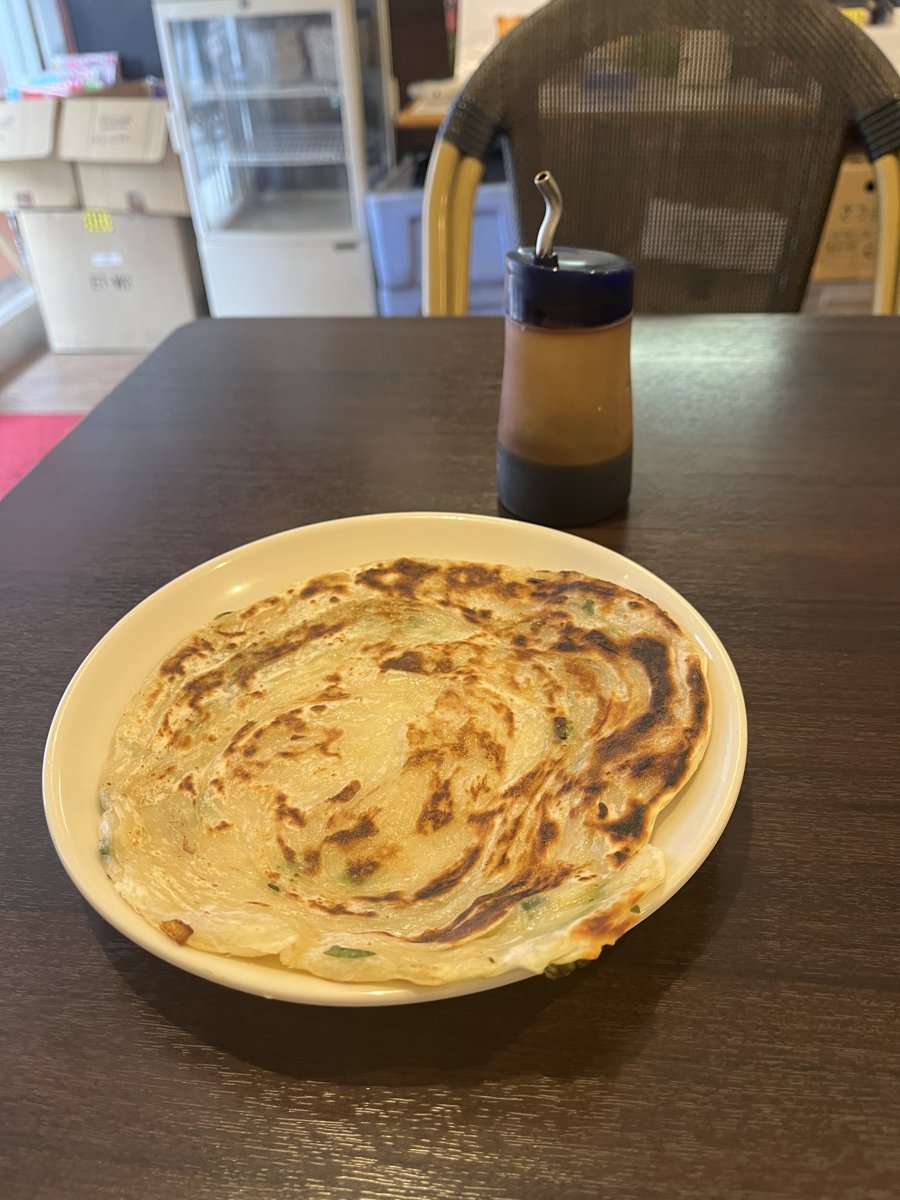 蔥抓餅(薄焼きねぎ餅)。白い皿に焼き色のついた薄いねぎ餅、奥に醤油ソースの瓶