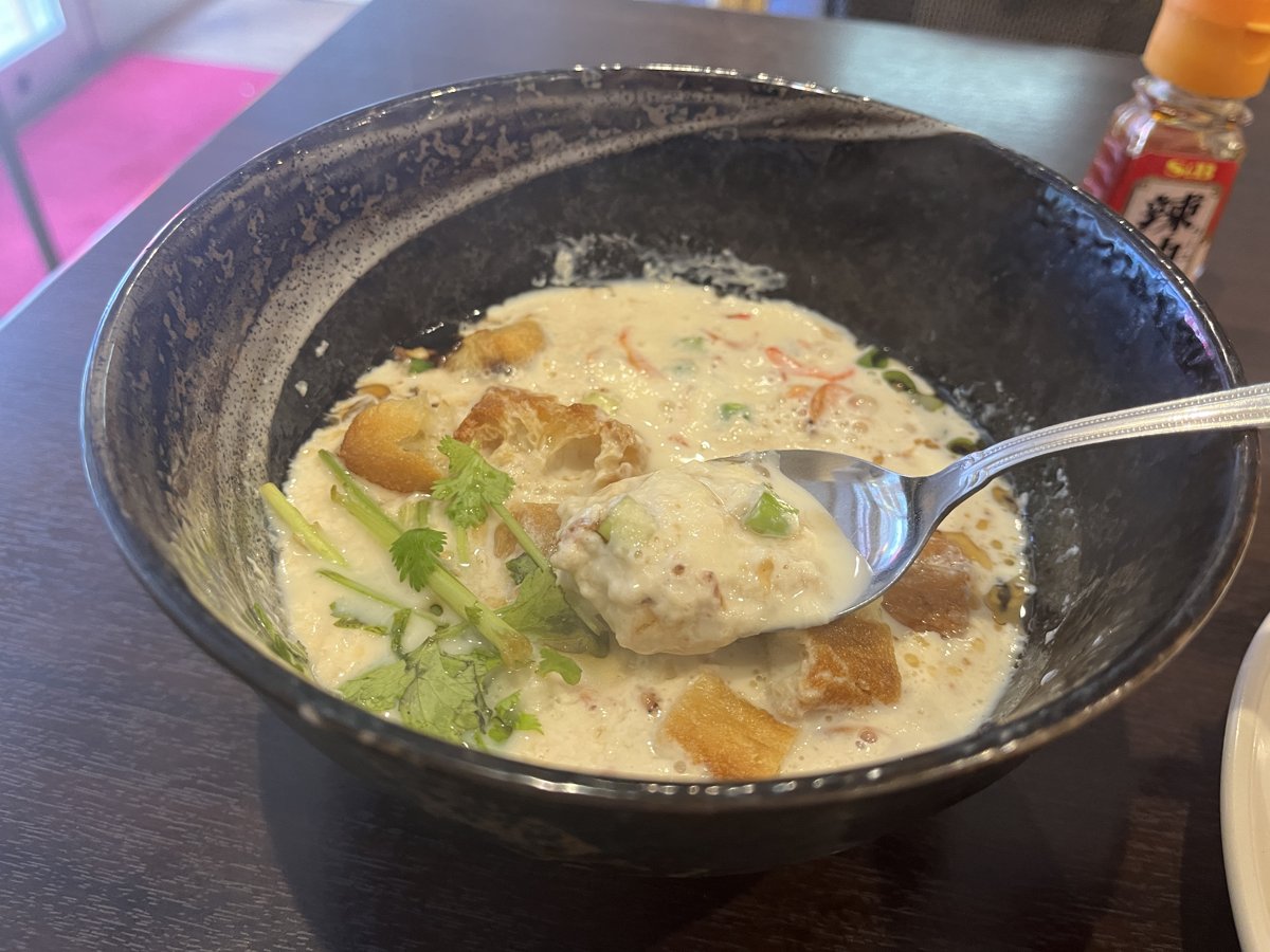 よく混ぜたあとのシェントウジャン。おぼろ豆腐状になった豆乳に揚げパンとパクチーが混ざっている