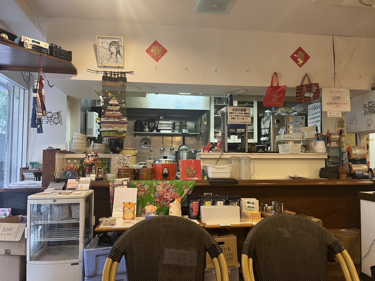浅草豆花大王の店内。カウンターの奥に厨房が見え、壁に赤い飾り、手前に編み目の椅子