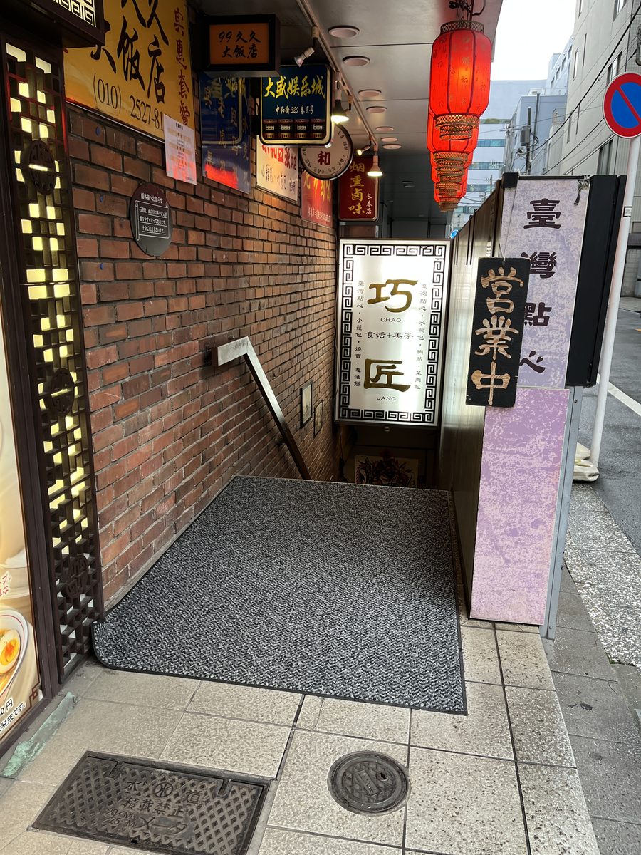 台湾点心屋台 巧匠の入口。れんがの壁の脇に巧匠の看板があり、赤い提灯の下から地下へ階段が続いている