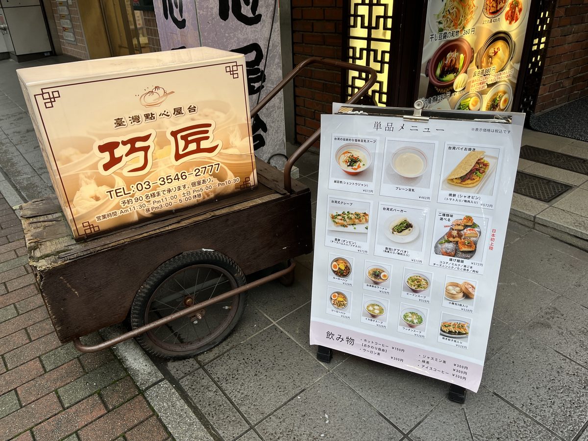 屋台の荷車にのせた巧匠の看板と、店頭の単品メニュー。鹹豆漿、プレーン豆乳、焼餅などが載っている