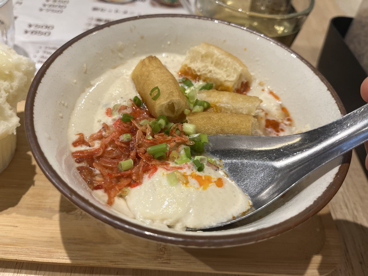 れんげですくったシェントウジャン。豆乳がかたまりのまますくえていて、器の中にはエビ、ねぎ、揚げパンが見える