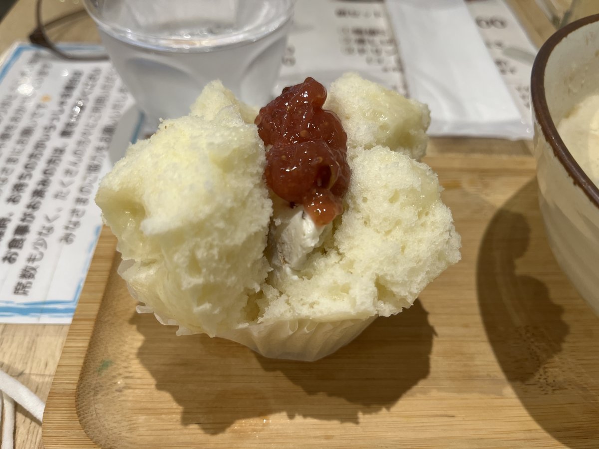 クリームチーズとくるみの蒸しパンの寄り。白い蒸しパンの割れ目にクリームチーズが入り、上に赤い具材がのっている