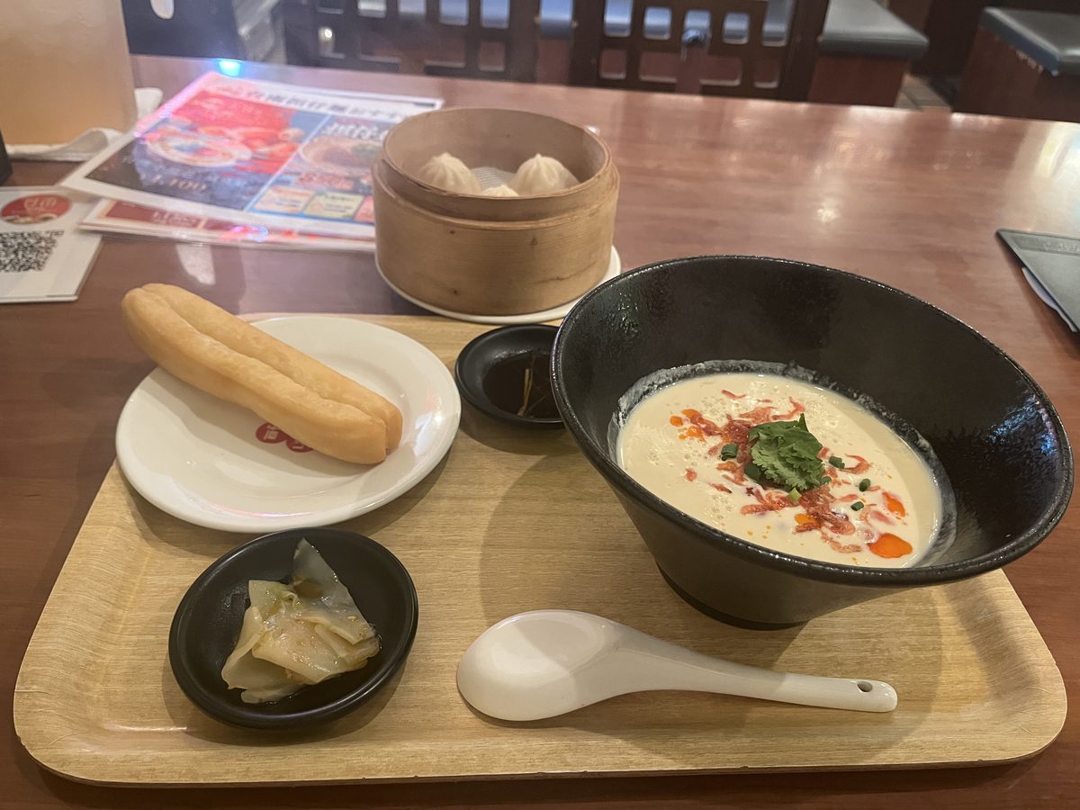 木のトレーにのったセット。シェントウジャン、別皿の揚げパン、せいろに入った小籠包3個、小皿のザーサイ