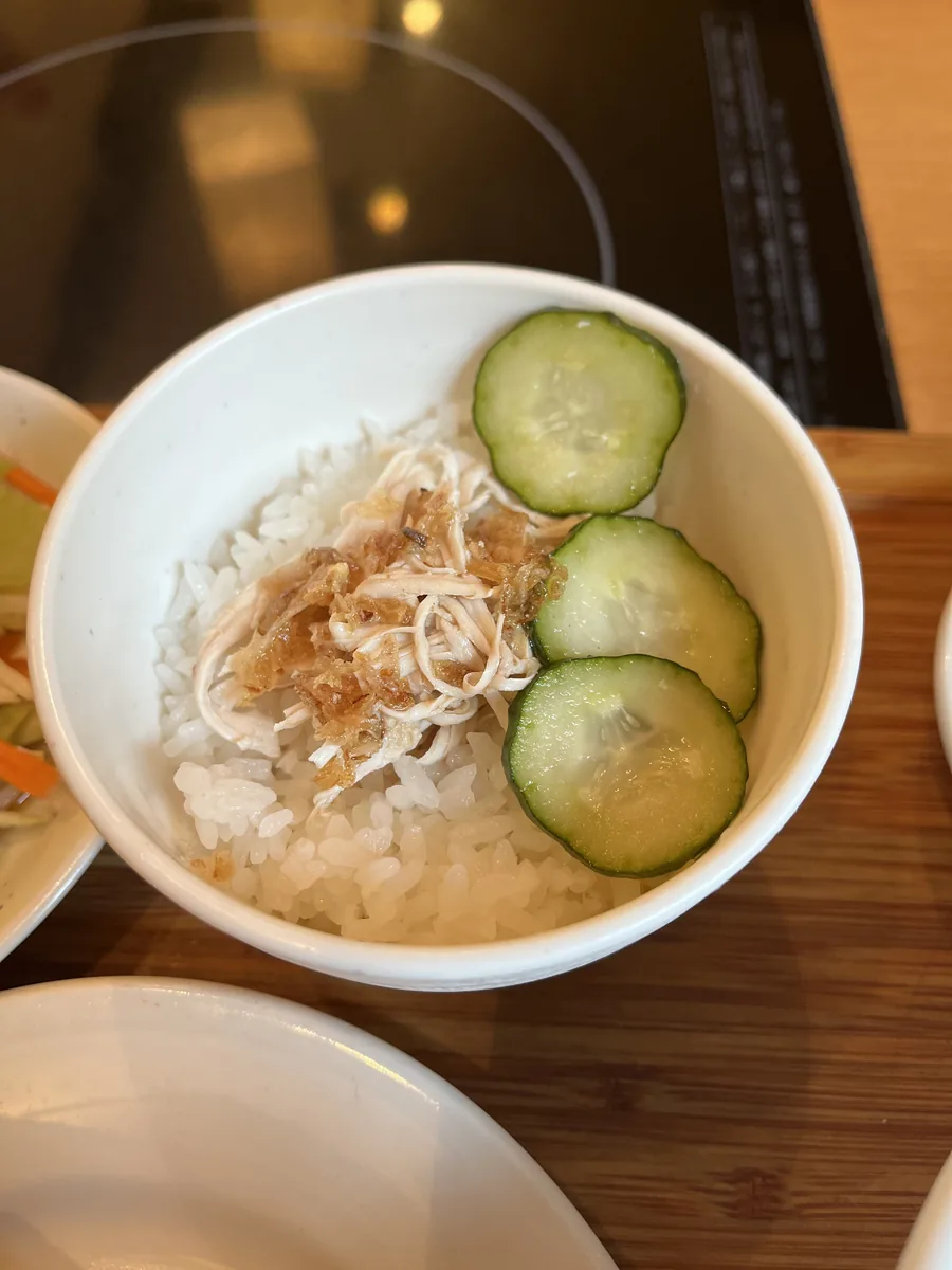 ミニ鶏肉飯。白いごはんに、ほぐした鶏肉ときゅうりの薄切りがのっている